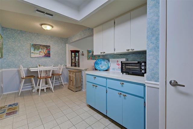 kitchen with white cabinets, blue cabinetry, and light tile floors