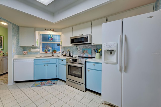 kitchen with appliances with stainless steel finishes, backsplash, white cabinets, sink, and light tile floors