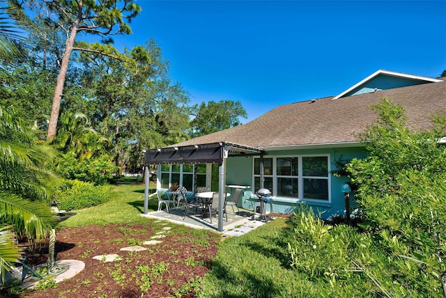 rear view of house featuring a patio area, a yard, and a pergola