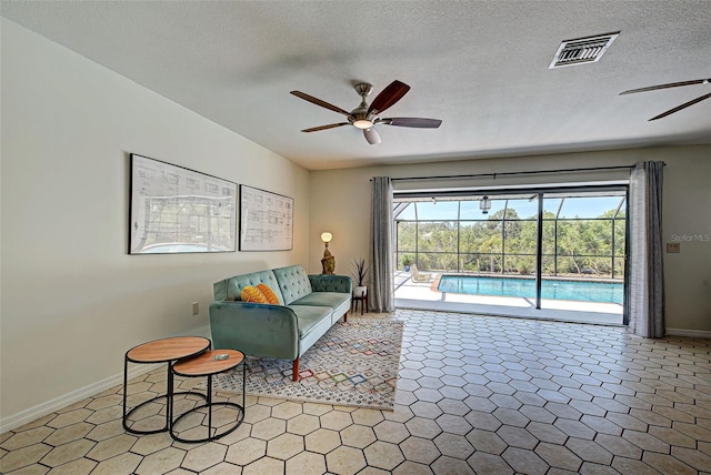 living room with ceiling fan, tile patterned flooring, and a textured ceiling