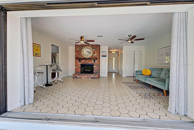 living room featuring a brick fireplace, ceiling fan, and light tile patterned floors