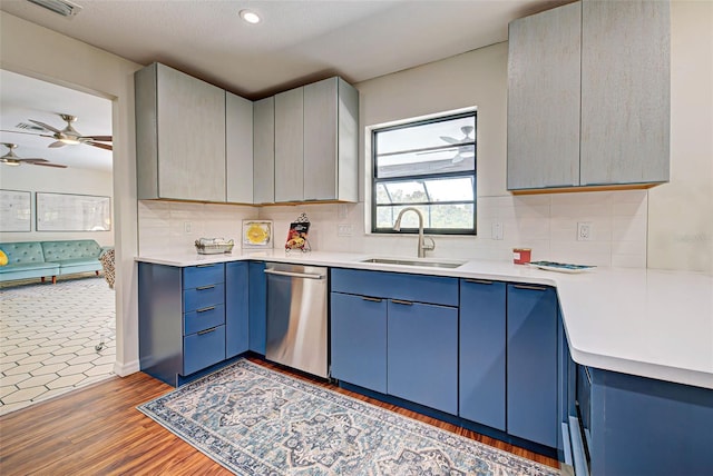 kitchen featuring tasteful backsplash, dishwasher, blue cabinetry, hardwood / wood-style floors, and sink