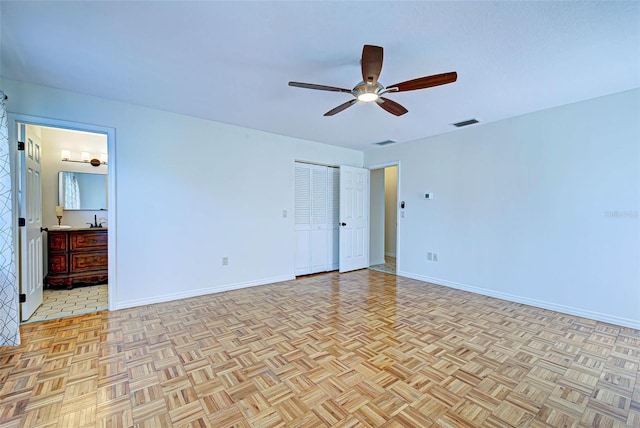 unfurnished bedroom featuring ceiling fan, sink, light parquet floors, and ensuite bathroom