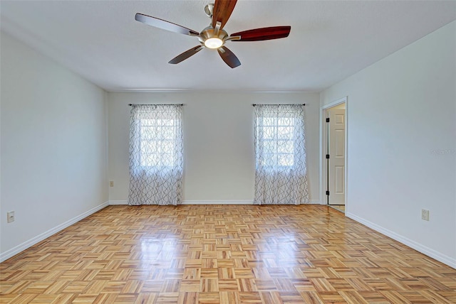 empty room featuring ceiling fan, plenty of natural light, and light parquet flooring