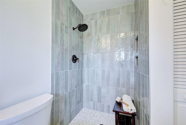 bathroom featuring a tile shower and toilet