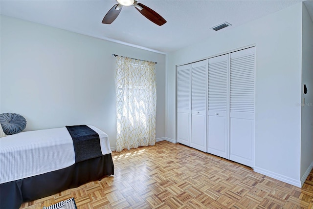 bedroom featuring ceiling fan, a closet, and light parquet floors