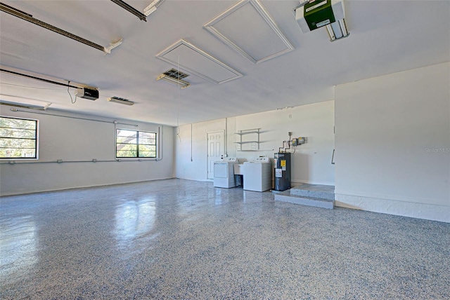 garage with a garage door opener, independent washer and dryer, and water heater