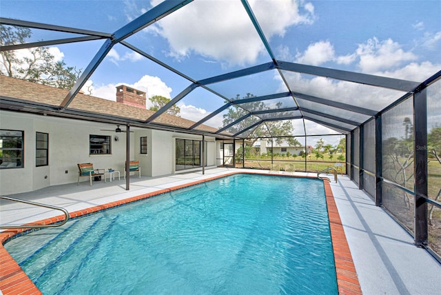 view of swimming pool with ceiling fan, a lanai, and a patio area