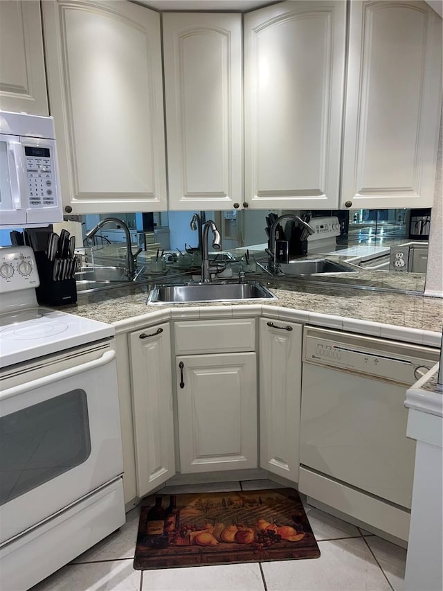 kitchen with white cabinetry, white appliances, sink, and light tile patterned floors