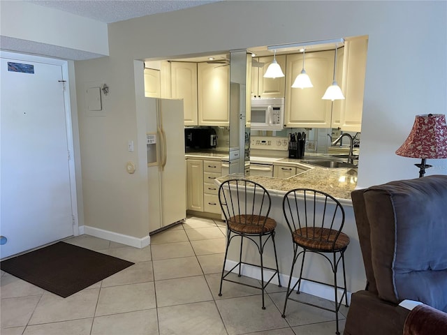 kitchen with white appliances, sink, hanging light fixtures, a kitchen bar, and kitchen peninsula