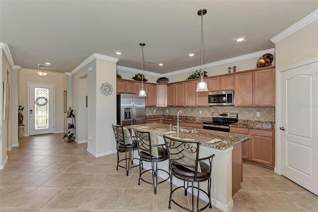 kitchen featuring light stone counters, a breakfast bar, stainless steel appliances, a center island with sink, and pendant lighting