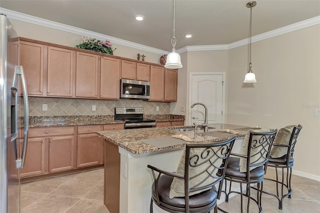 kitchen featuring hanging light fixtures, stainless steel appliances, sink, light stone counters, and a center island with sink