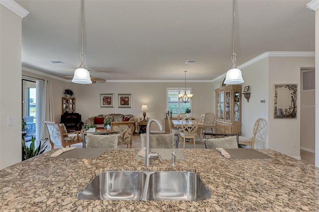 kitchen featuring a healthy amount of sunlight, sink, crown molding, and light stone counters