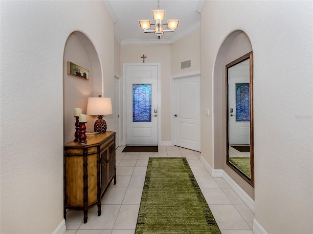 tiled entryway with crown molding and a chandelier