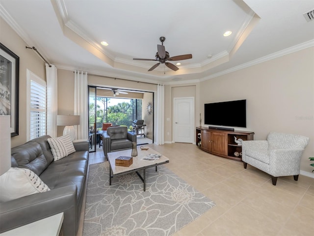 tiled living room with ornamental molding, ceiling fan, and a raised ceiling