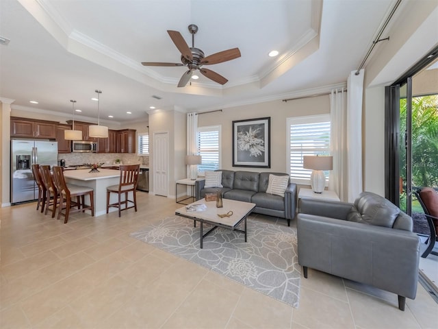 tiled living room featuring a healthy amount of sunlight, a raised ceiling, and crown molding