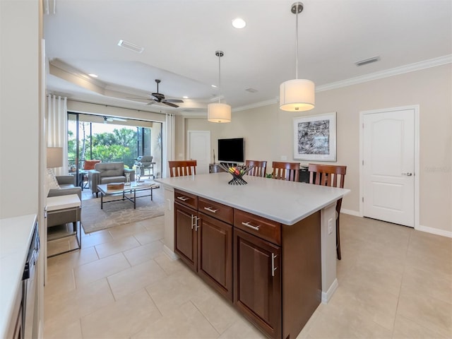 kitchen featuring dark brown cabinets, ceiling fan, pendant lighting, a center island, and ornamental molding