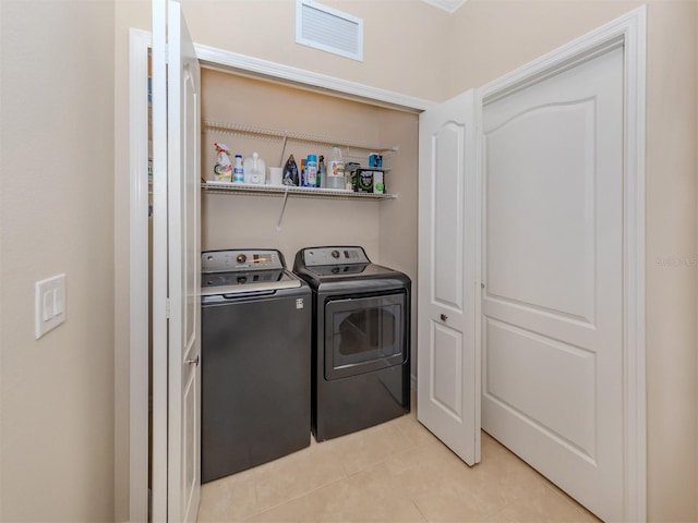 laundry area featuring washing machine and clothes dryer and light tile floors