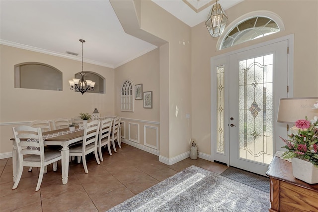 foyer entrance with a notable chandelier, ornamental molding, and light tile patterned floors