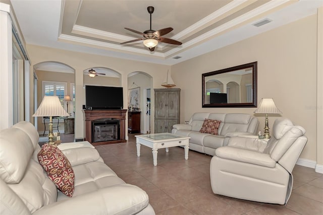 tiled living room featuring a raised ceiling and ceiling fan