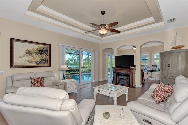 living room featuring a raised ceiling and ceiling fan