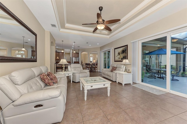 living room with ceiling fan, light tile patterned floors, and a tray ceiling