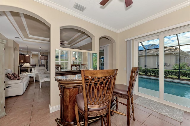 dining space with a raised ceiling, ceiling fan, crown molding, and tile patterned flooring