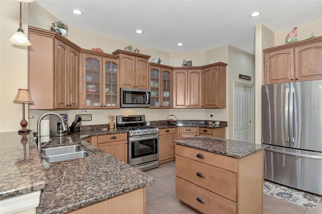 kitchen with decorative light fixtures, stainless steel appliances, sink, dark stone countertops, and light tile patterned floors