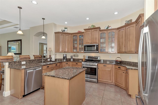 kitchen with appliances with stainless steel finishes, a center island, light tile patterned floors, and sink