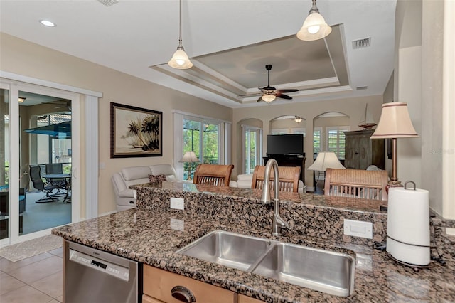 kitchen featuring stainless steel dishwasher, ceiling fan, a tray ceiling, sink, and light tile patterned floors