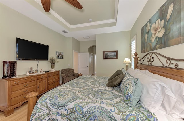 bedroom with ceiling fan, light hardwood / wood-style flooring, and a raised ceiling