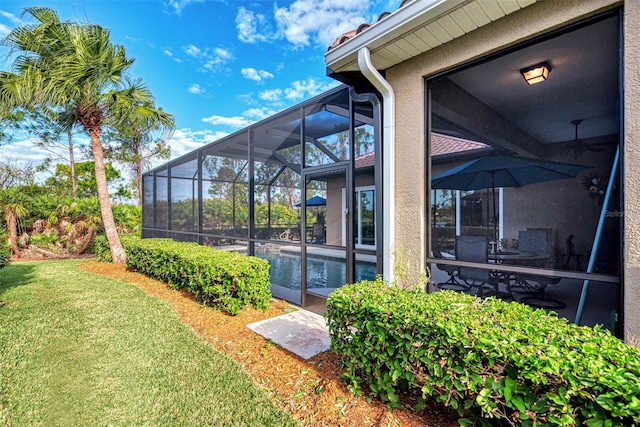 exterior space featuring glass enclosure and a lawn