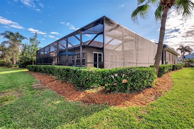 view of side of property with a yard and glass enclosure