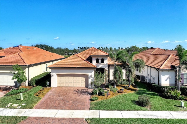 mediterranean / spanish home featuring a garage, central AC, and a front lawn