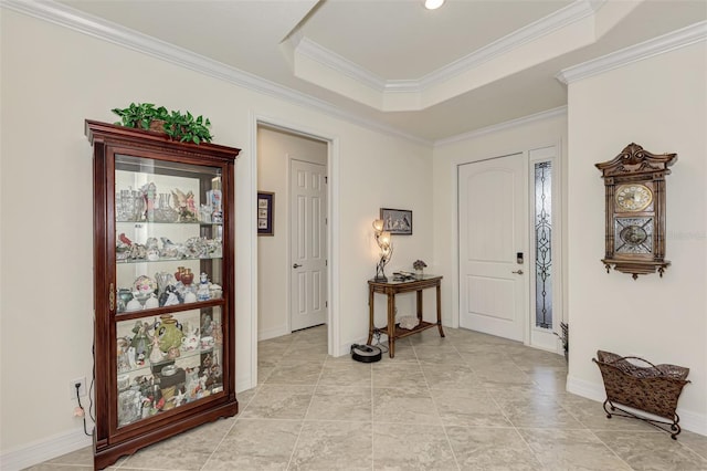 tiled entryway with a tray ceiling and crown molding