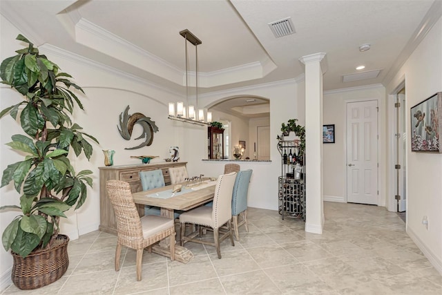 tiled dining area featuring ornate columns, a tray ceiling, a chandelier, and ornamental molding