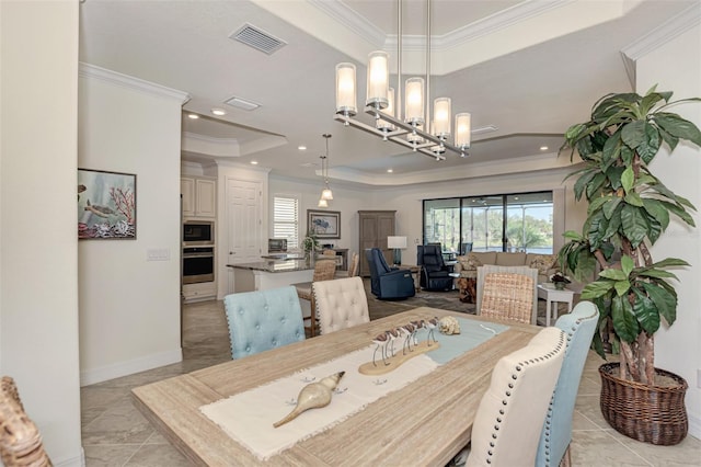 tiled dining space featuring a chandelier, ornamental molding, and a tray ceiling