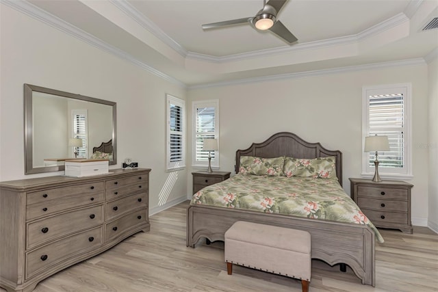 bedroom with multiple windows, a raised ceiling, and light wood-type flooring