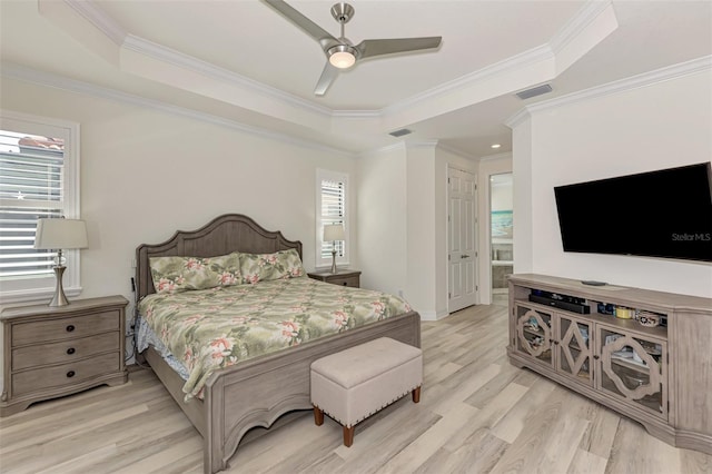 bedroom with ensuite bath, light wood-type flooring, ceiling fan, and a tray ceiling