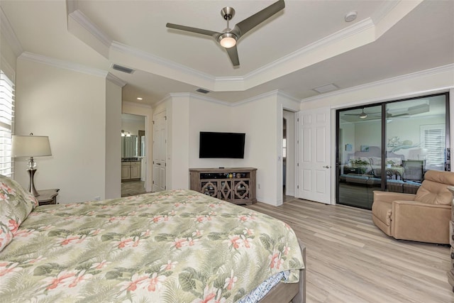 bedroom with light hardwood / wood-style flooring, a tray ceiling, and ornamental molding