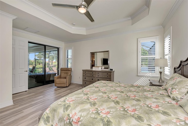 bedroom with a raised ceiling, light wood-type flooring, access to exterior, and multiple windows