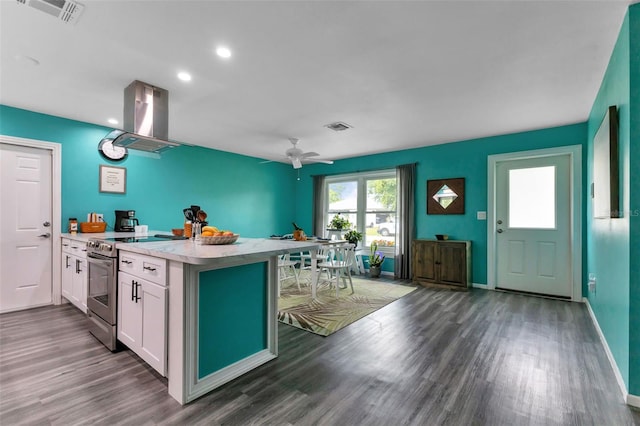 kitchen featuring ceiling fan, white cabinets, dark wood-type flooring, stainless steel range with electric cooktop, and island exhaust hood