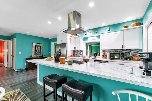 kitchen featuring backsplash, appliances with stainless steel finishes, white cabinetry, dark hardwood / wood-style flooring, and island exhaust hood