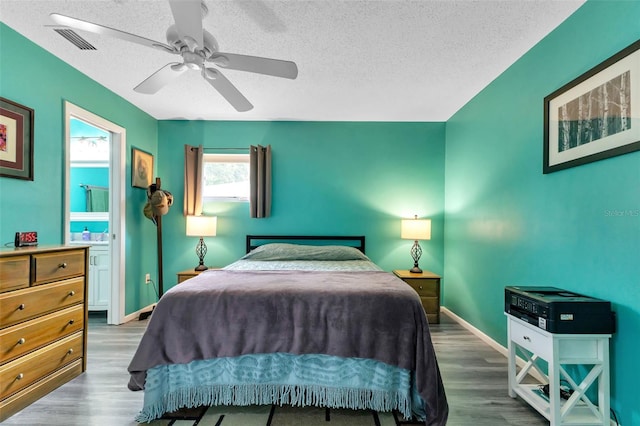 bedroom with ceiling fan, hardwood / wood-style flooring, and a textured ceiling