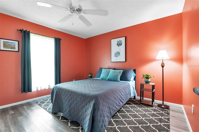 bedroom featuring a textured ceiling, multiple windows, ceiling fan, and dark wood-type flooring