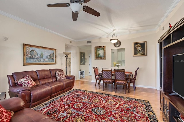 living room featuring ceiling fan, crown molding, and light wood-type flooring