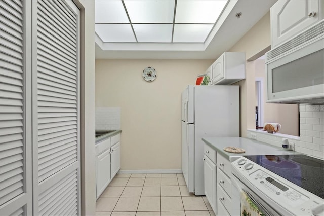 kitchen with backsplash, white cabinets, light tile floors, and white appliances