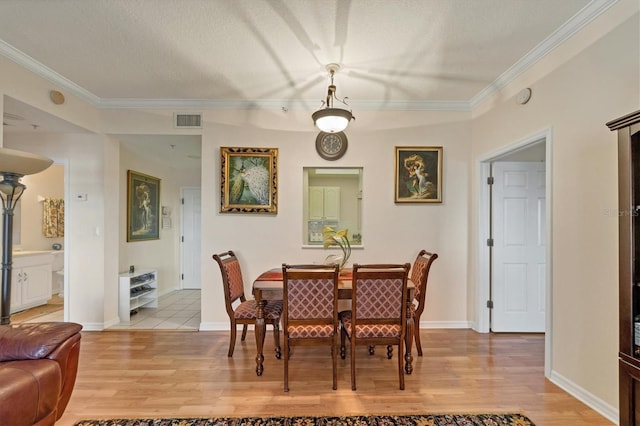 dining area featuring light hardwood / wood-style flooring, crown molding, and a textured ceiling