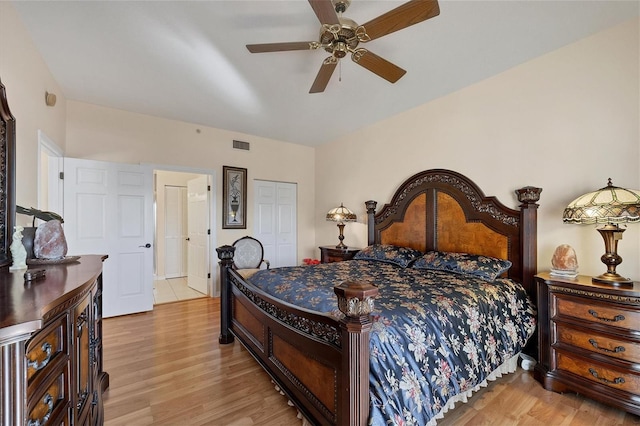 bedroom featuring a closet, light hardwood / wood-style floors, ceiling fan, and ensuite bath