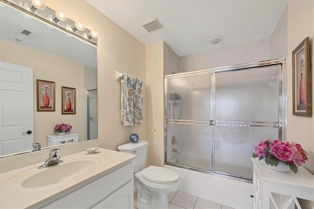 full bathroom with bath / shower combo with glass door, toilet, a textured ceiling, vanity, and tile floors